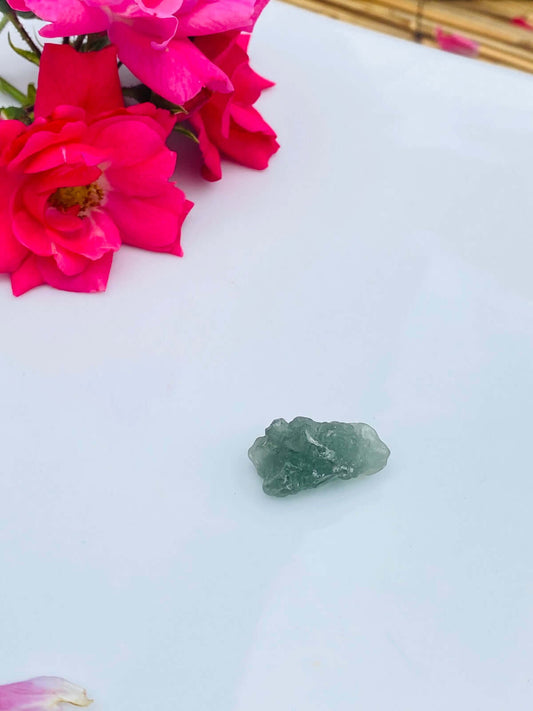 Ein Stück grüner MOLDAVIT auf weißem Porzellan.