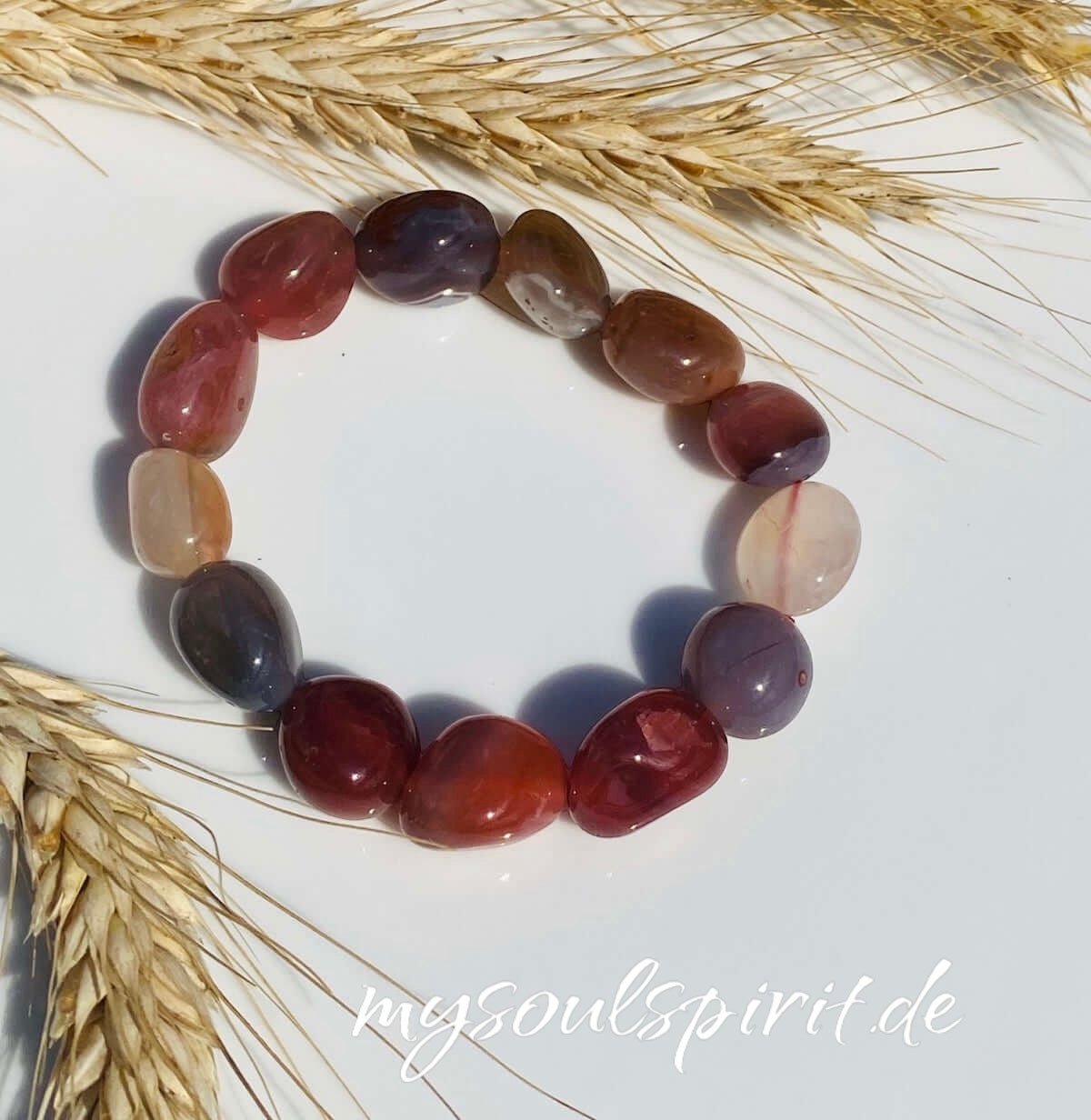 Trommelstein-Armband auf weißem Untergrund mit Weizendeko