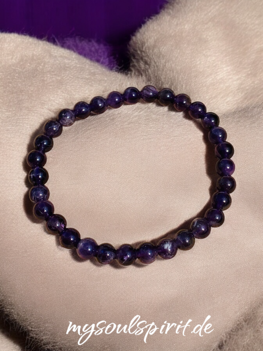 Armband mit 6 mm Perlen aus lila Amethyst auf Stoffkissen.